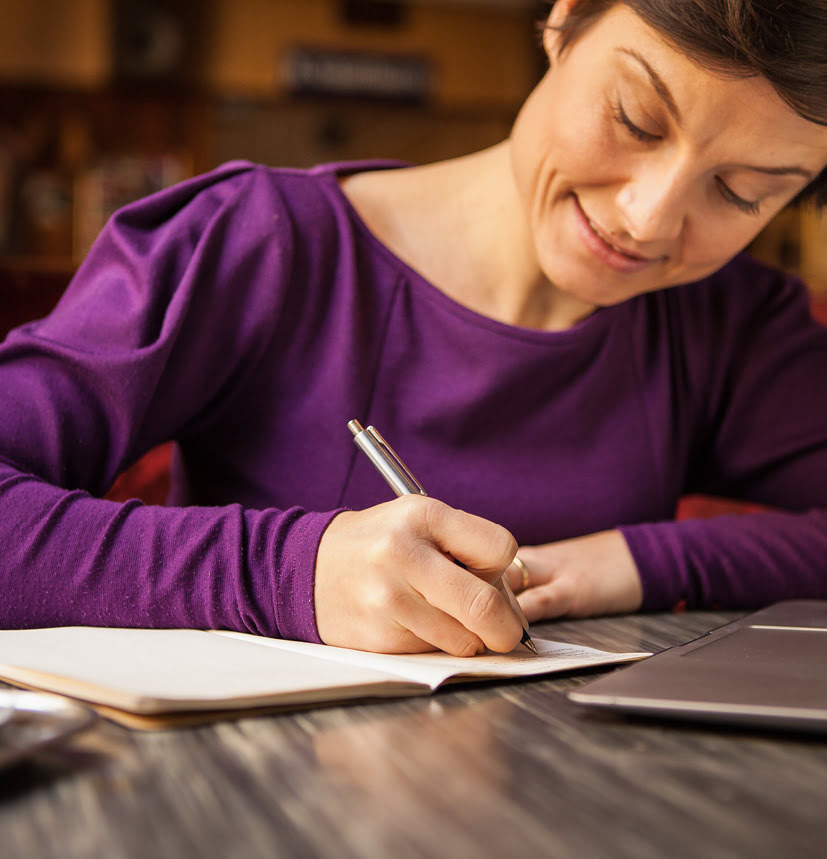 Lena Raubaum schreibt gut gelaunt und hochkonzentriert in ein Notizheft.